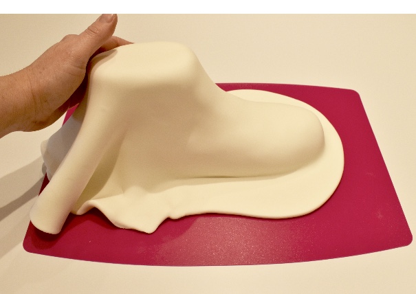 Knead 1kg of white Renshaw Extra sugarpaste and cover the carved boot cake using your hand to smooth around the contours of the cake.