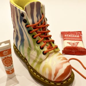 Mix orange Pro Gel colour into 40g of Renshaw modelling paste. Roll out two long sausage strips to make laces for the boot. Cut each section and glue in place starting from the bottom of the lace inserting into each eyelet.