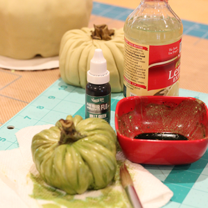 Do the same for the green squash that will be placed onto the board using a mixture of ivory, green and brown fondant to achieve a muted green colour. Dust and colour wash the pumpkins and stems.
