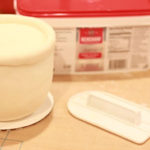 Once the cakes are chilled and firm, cover the top two tiers in ivory fondant.