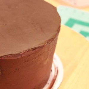 Starting with the bottom tier, place a piece of brown fondant over the covered cake, leaving the sides of the cake with only the ganache.