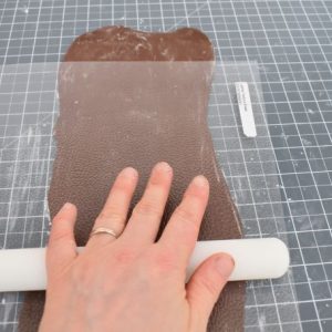 Roll out some dark modelling chocolate and press the leather impression mat over it.