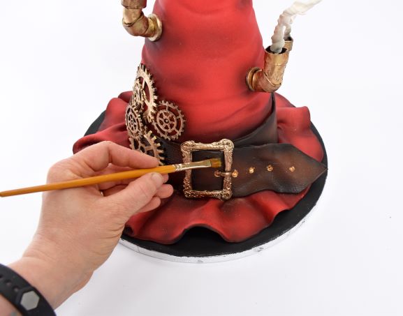 Paint the belt with confectioners’ glaze to give it shine. Don’t forget the ribbon!
